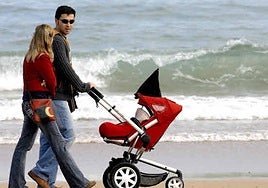 Una pareja pasea por la playa con su hijo.