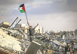 Un niño ondea una bandera palestina sobre los escombros de un edificio destruido en el campamento de refugiados de Bureij.