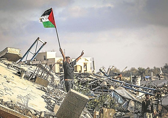 Un niño ondea una bandera palestina sobre los escombros de un edificio destruido en el campamento de refugiados de Bureij.