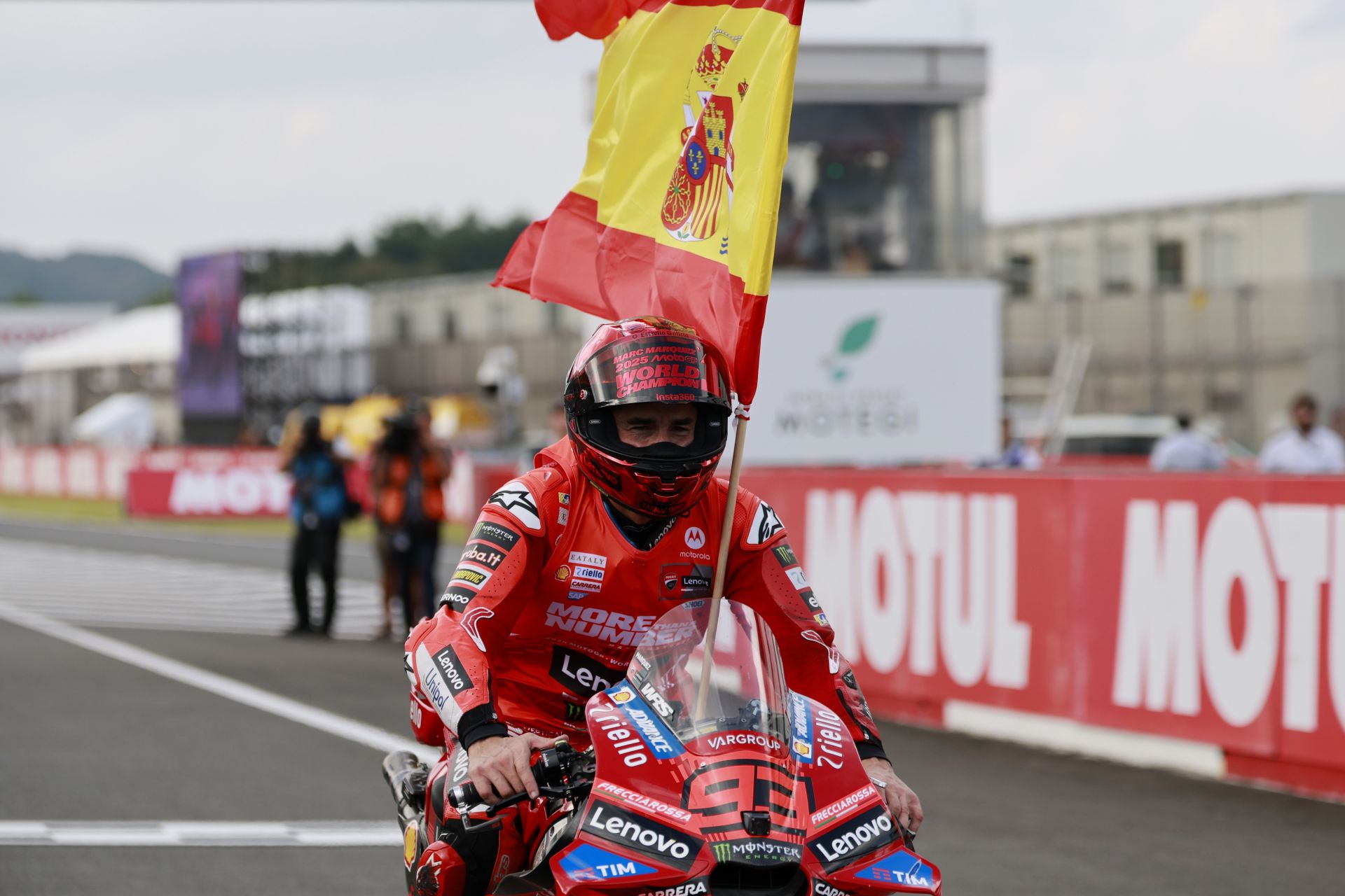 Marc Márquez pasea la bandera española por el circuito de Motegi tras proclamarse este domingo campeón del mundo de MotoGP por séptima vez.