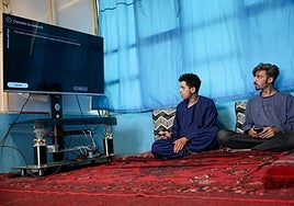 Dos hombres tratan de conectar sin éxito en Kabul su televisor a internet.
