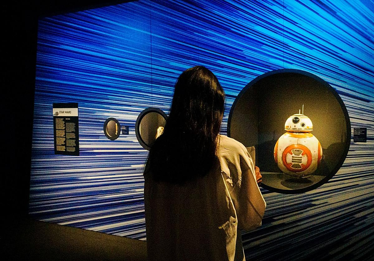 Una joven observa la marioneta del androide BB-8 utilizada en 'Star Wars: El despertar de la fuerza'.