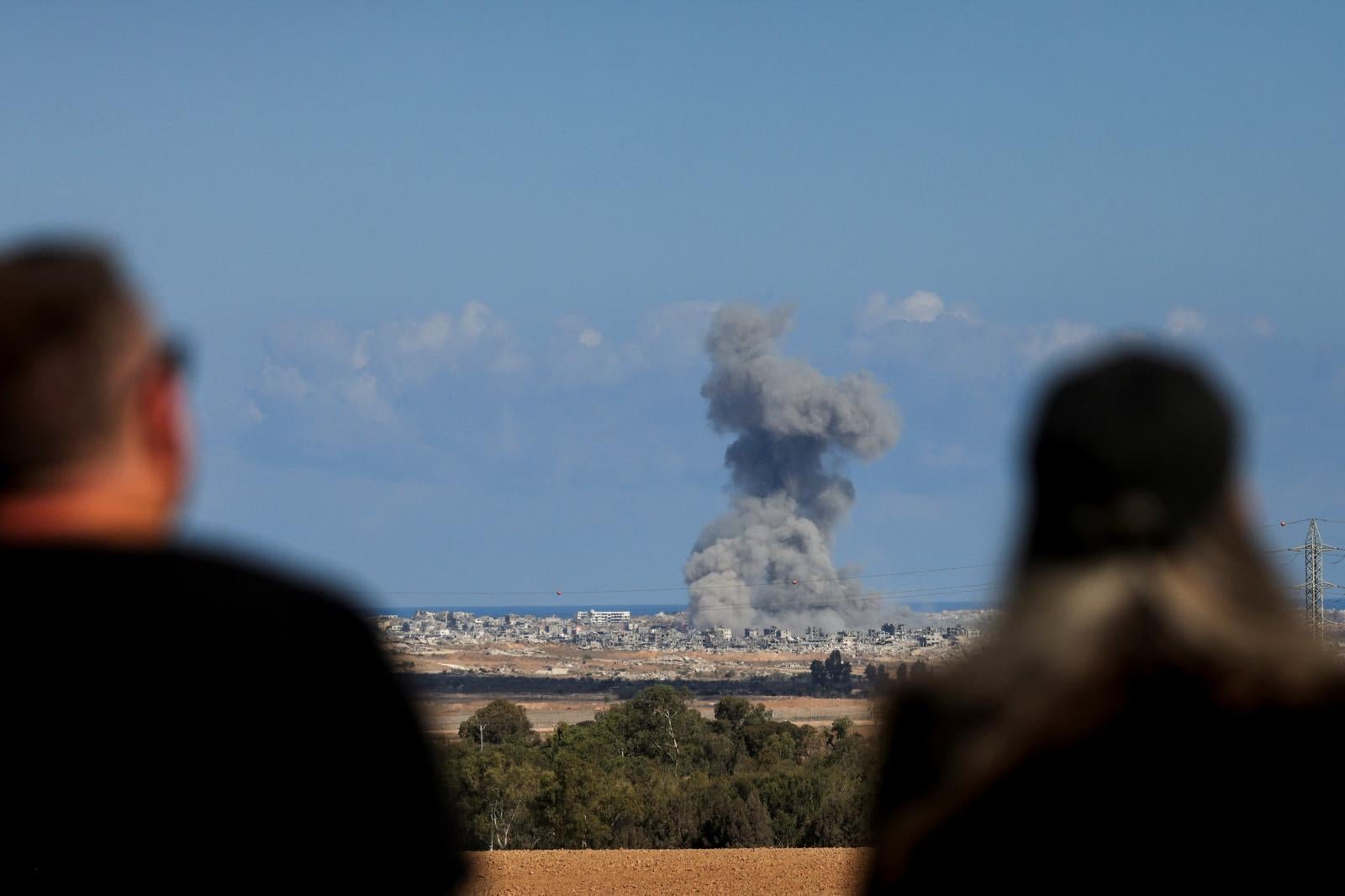 Dos personas observan una explosión en la Franja de Gaza.