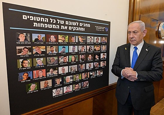 Benjamín Netanyahu observa el panel con las fotos de los rehenes aún sin liberar de camino a la sesión del Consejo de Seguridad israelí.