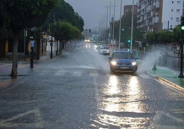 Un choce salpica agua en un paso de peatones en Cartagena.
