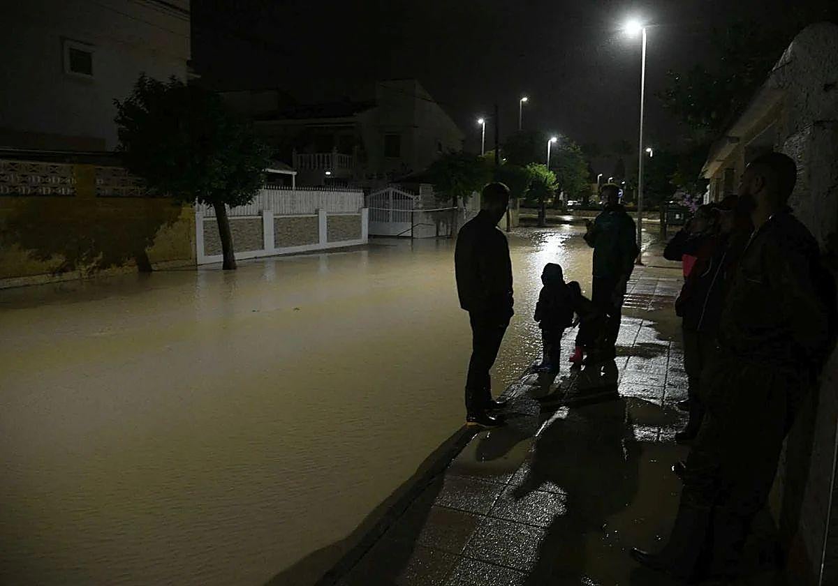 Vecinos de Los Alcázares, de madrugada, en una calle inundada.