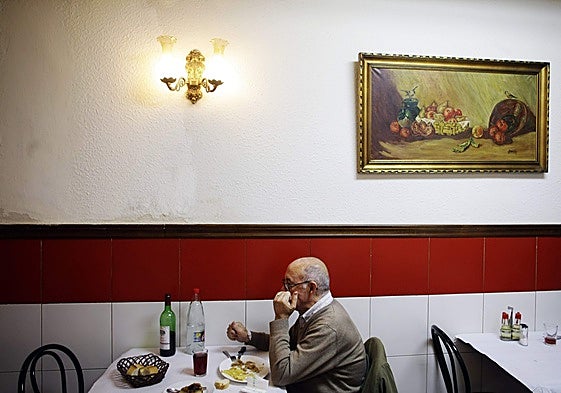 Un jubilado toma un menú en una casa de comidas.