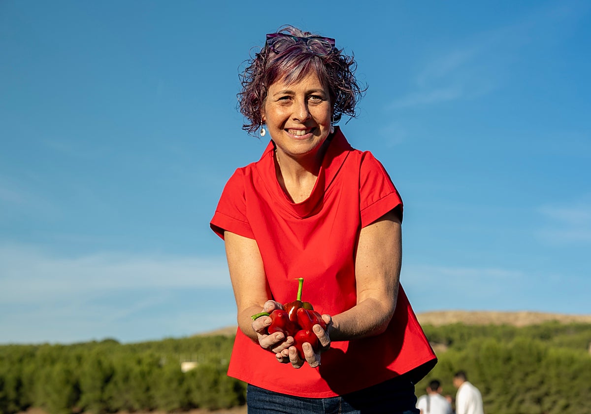 Una mujer sujeta un puñado de pimientos recién cogidos en un huerto de Lodosa.