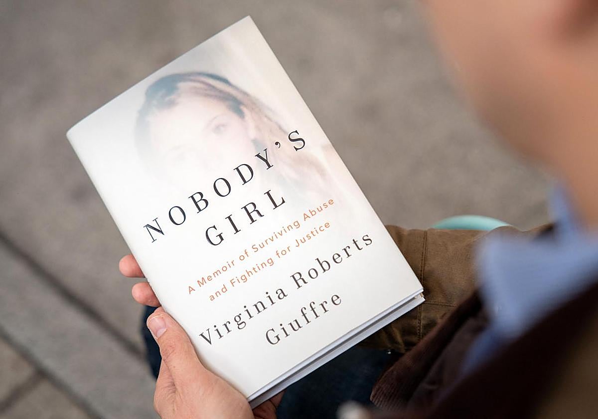 Un lector sostiene un ejemplar de las memorias póstumas de Virginia Giuffre, víctima de abusos sexuales del entramado Epstein.