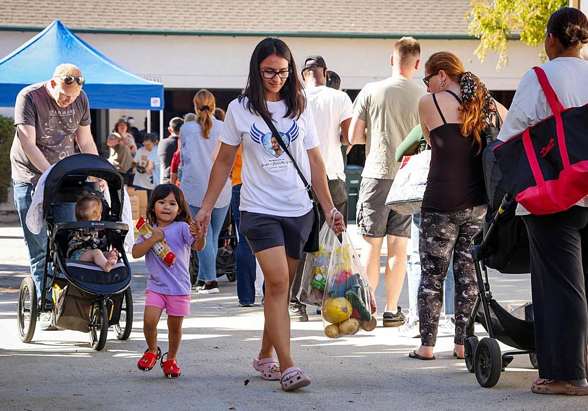 Grupos de familias hacen cola para recibir donativos de alimentos en San Diego, California.