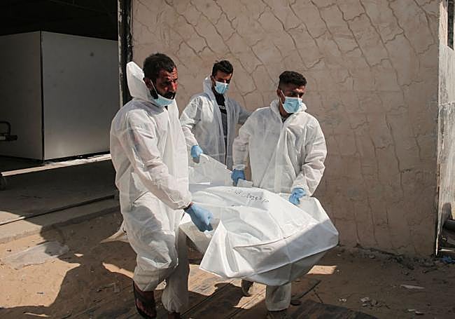 Empleados del complejo médico Nasser transportan una bolsa con uno de los treinta cuerpos de prisioneros palestinos devueltos por Israel.