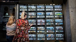 Dos mujeres miran ofertas de viviendas en una inmobiliaria.