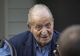 El rey emérito saluda ayer desde un coche tras aterrizar en el aeropuerto vigués de Peinador.