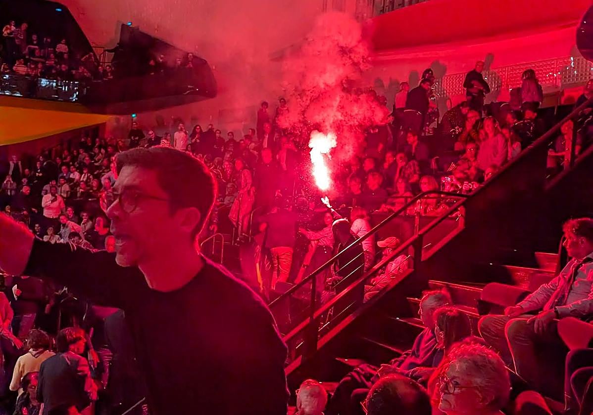 Un activista prende una bengala en la sala de conciertos de la Filarmónica de París.