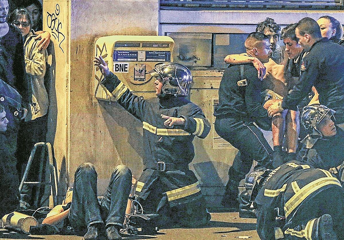 Miembros del cuerpo de bomberos francés auxilian a un joven herido cerca de la sala de conciertos Bataclan.
