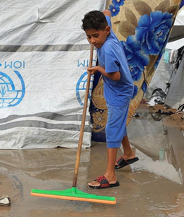 Imagen secundaria 2 - Una mujer con un crío en brazos entre los restos de la guerra en Ciudad de Gaza; edificios reducidos a escombros en el barrio de Radwan, en el norte de la Franja; un niño trata de empujar el agua tras las lluvias sobre el enclave. 