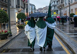 Nazarenos se protegen de la lluvia en la Semana Santa en Granada.