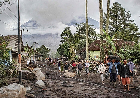 Residentes locales se trasladan a lugares seguros tras la erupción del volcán Semeru.