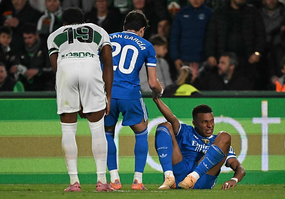 Fran García ayuda a Mbappé a levantarse.