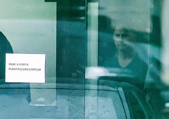 Bolsonaro es visto a través de una puerta acristalada de la sede de la Policía Federal de Brasilia, donde se encuentra recluido desde el sábado.