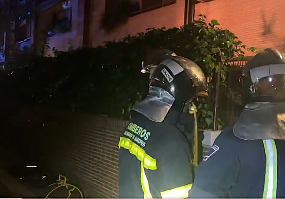 Dos bomberos frente a la vivienda incendiada