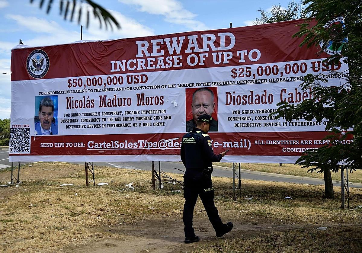 Un policía colombiano camina frente a un cartel que ofrece una recompensa millonaria por la detención de Nicolás Maduro y Diosdado Cabello, a quienes EE UU acusa de liderar el Cártel de los Soles.