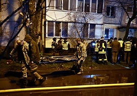 Bomberos transportan un cuerpo fuera de un edificio residencial dañado tras un ataque ruso en Kiev.