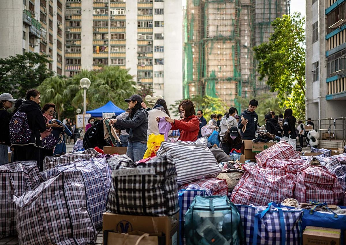 Imagen secundaria 1 - Varios residentes en las torres calcinadas pasan la noche en un centro comerciales: decenas de bolsas con artículos de primera necesidad para los damnificados; rescatistas portan varias mascotas. 