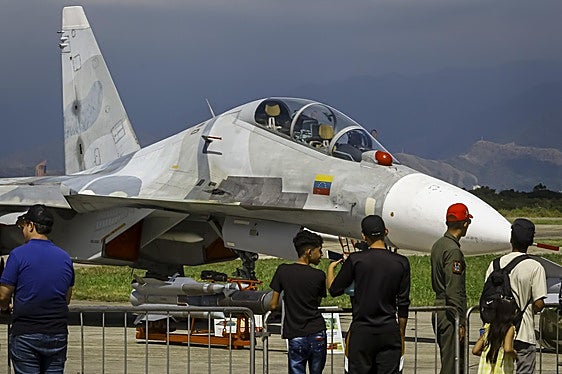 Un grupo de venezolanos observa un avión de combate durante una feria aeronáutica celebrada este fin de semana en Maracay.