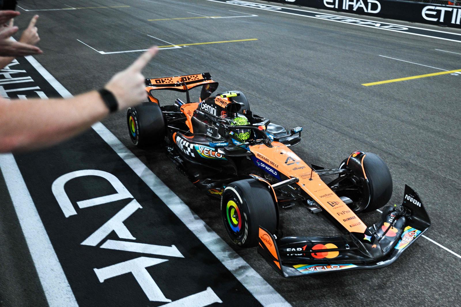 Lando Norris pasa por delante del muro de su equipo, que celebra el título.