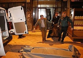 Los servicios funerarios trasladan el cuerpo del fallecido.