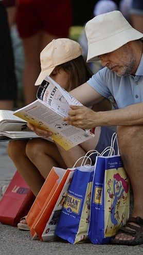 Imagen secundaria 2 - La Reina, en un taller con niños y paseando junto con Eva Orúe y Ernest Urtasun. Dos lectores en el Retiro.