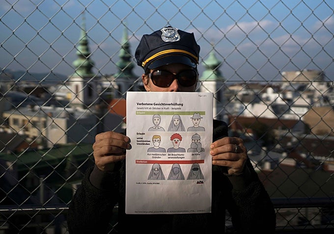 Un agente muestra un cartel con otras medidas sobre la vestimenta en vigor en Austria.