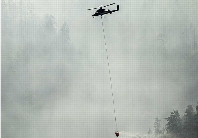 Un helicóptero se prepara para descargar agua en uno de los incendios en pleno bosque.