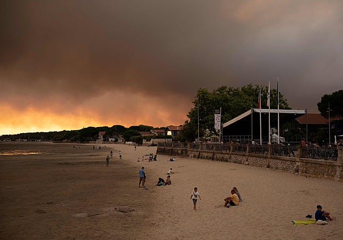 Bañistas en la playa de Andernos-Les Bains con el fuego al fondo.