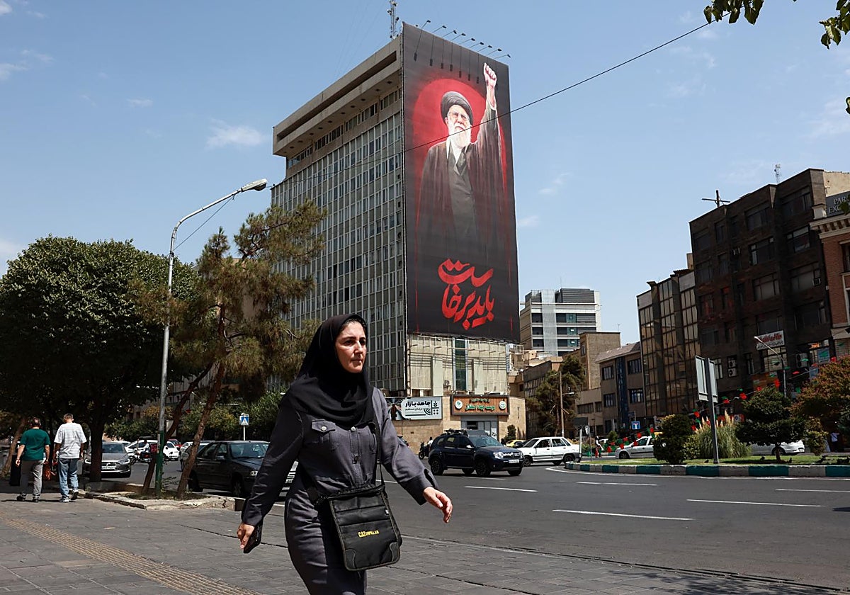 Una mujer camina por Teherán cerca de un mural del fallecido Ali Jamenei, padre del actual Líder Supremo.