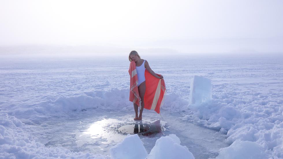 Elina se protege con una toalla tras darse un chapuzón en un 'avanto' abierto en un septentrional lago finlandés.