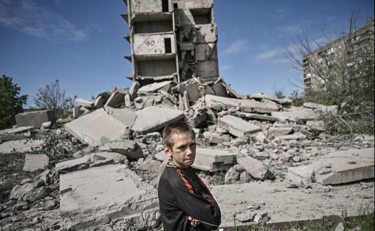 Un niño posa delante de las ruinas de un edificio tras ser bombardeado por las tropas rusas en la región de Donetsk.