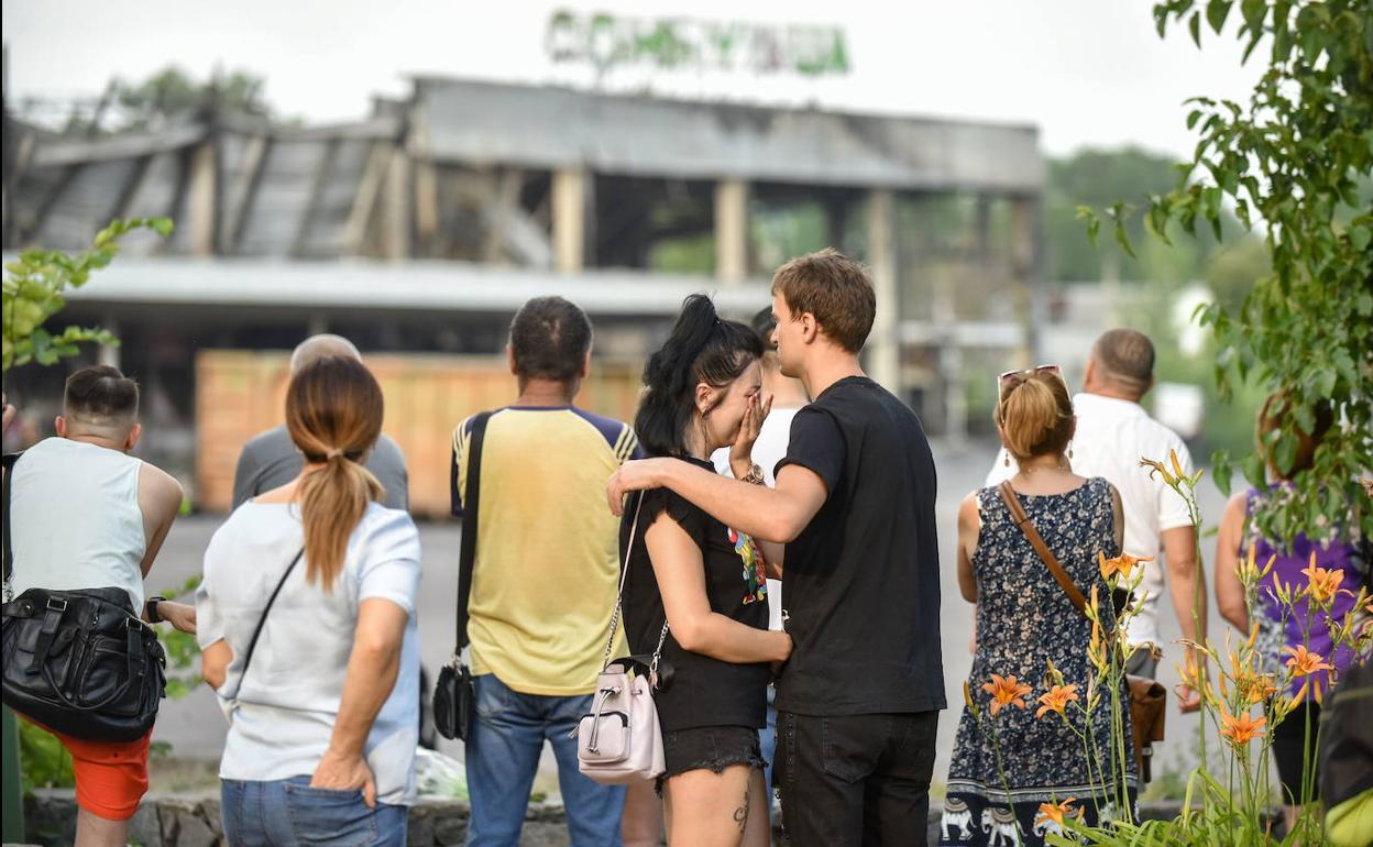 Un grupo de personas llora ante el centro comercial destrozado por el misil. 