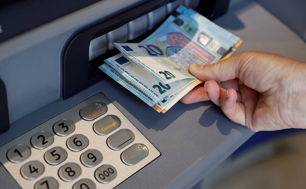 Una persona saca dinero del cajero. 