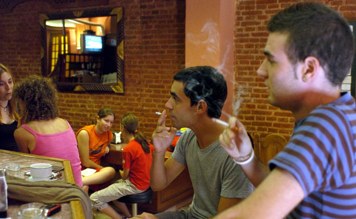 Un grupo de jóvenes fuma cigarrillos en un bar de Madrid. 