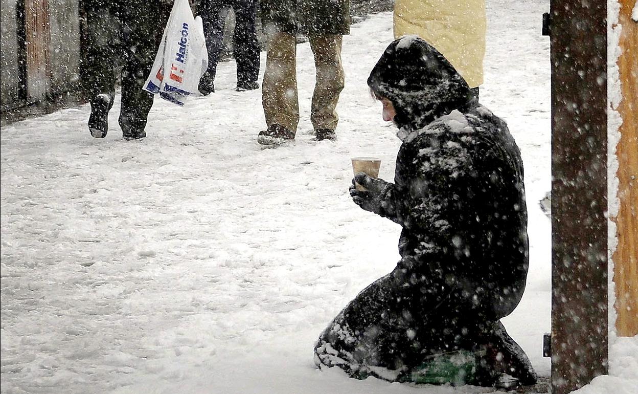 Una mujer pide en una calle nevada en Madrid.