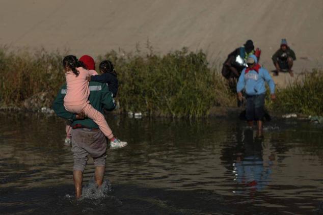 Un grupo de migrantes cruza el río Bravo desde Ciudad Juárez (México) hacia El Paso (Texas).