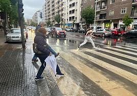 Varias personas intentan cruzar la calle anegada de agua