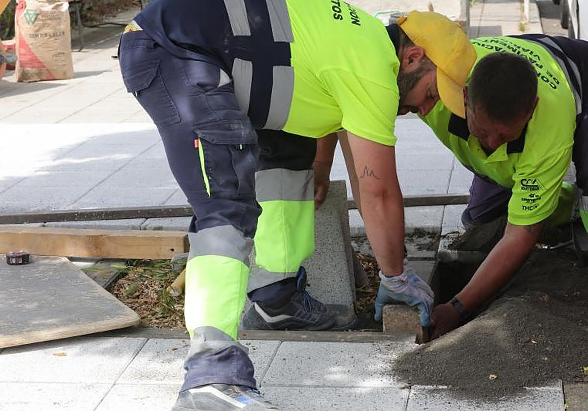 Dos obreros realizan un trabajo en la calle.