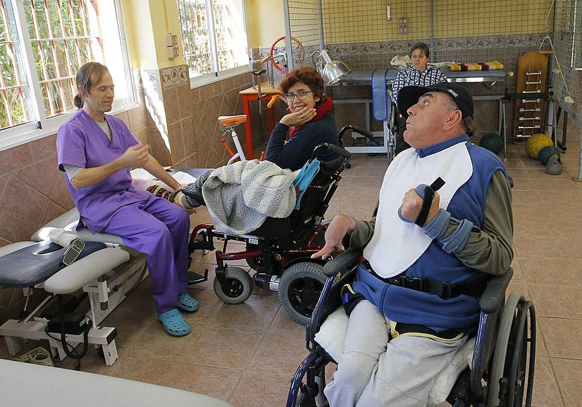 Imagen de archivo de un trabajador ayudando a personas con discapacidad.