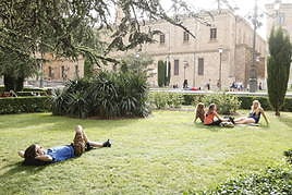 Personas tumbadas en el césped descansando en un día caluroso en Salamanca.