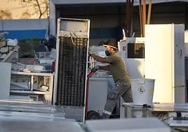 Un trabajador retira una nevera que no funciona.