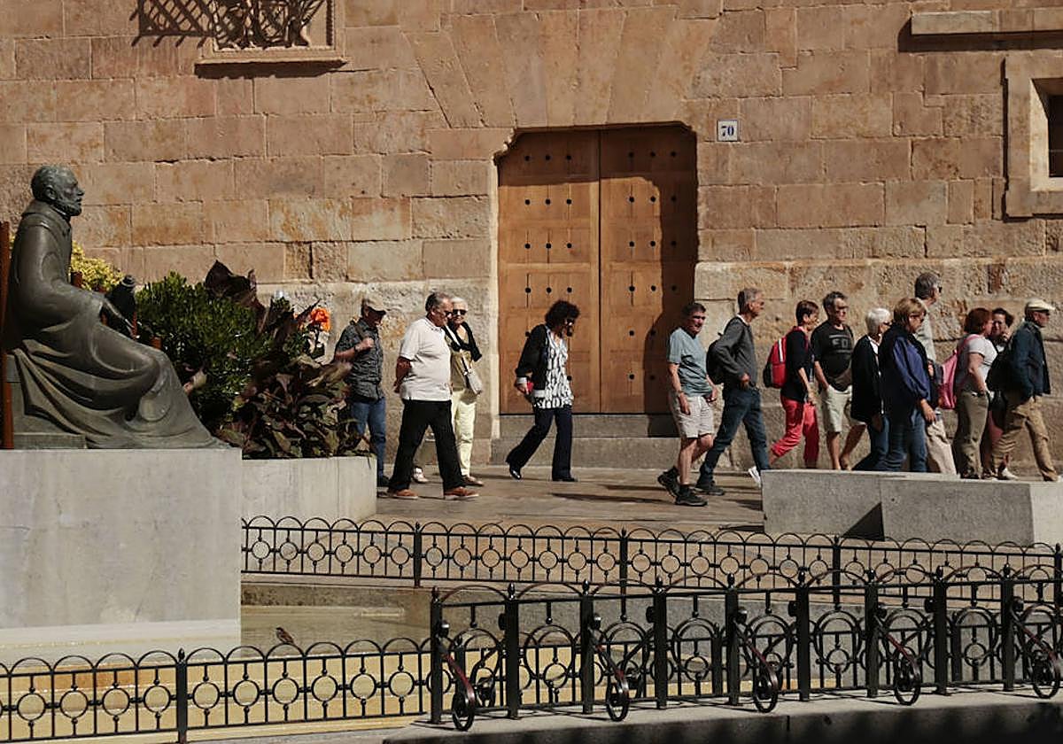 Varios turistas pasean junto a la Casa de las Conchas de Salamanca.