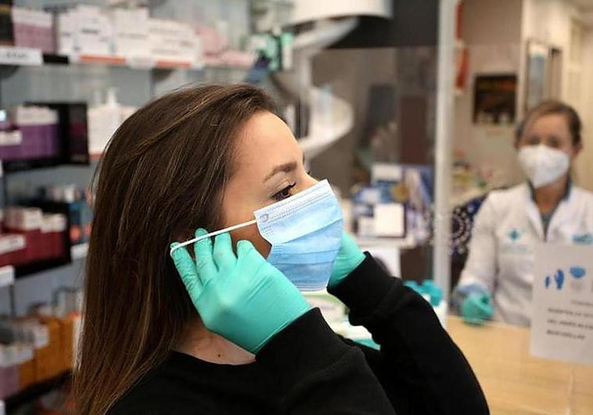 Una mujer se coloca una mascarilla en una farmacia.